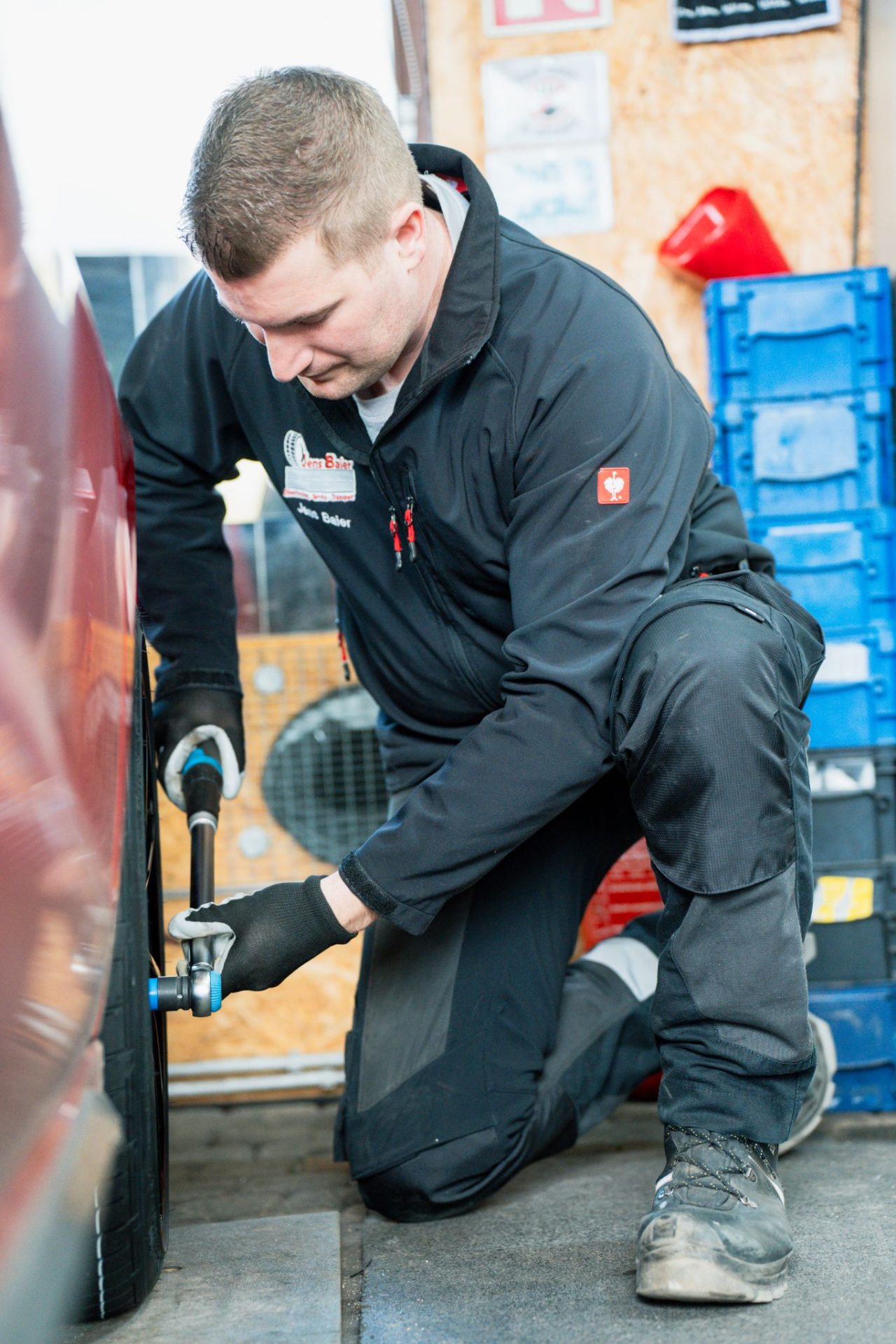 Mechaniker kniend am Fahrzeug in der Werkstatt