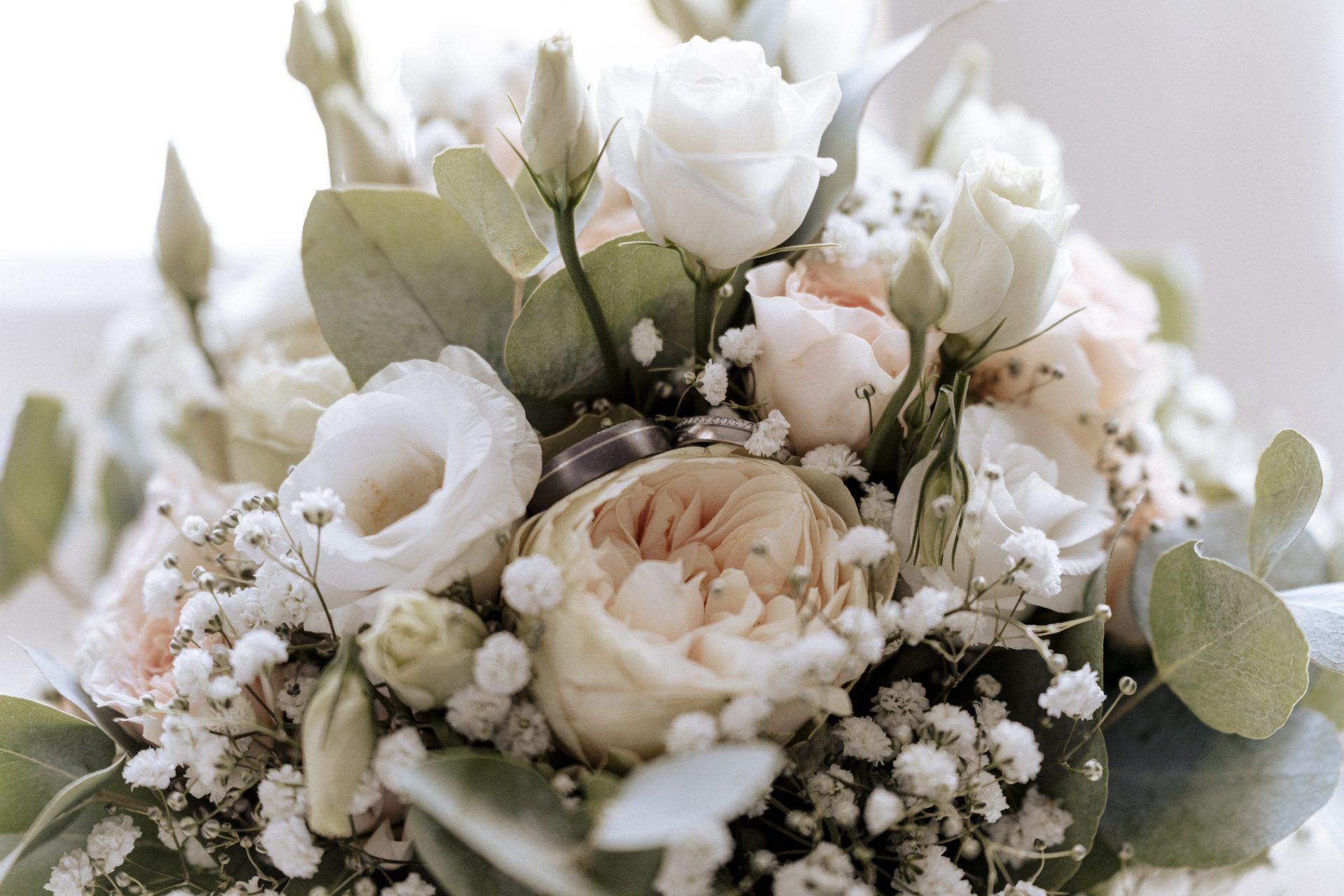 Brautstrauß mit weißen Rosen, Schleierkraut und Eukalyptus in hellem Licht