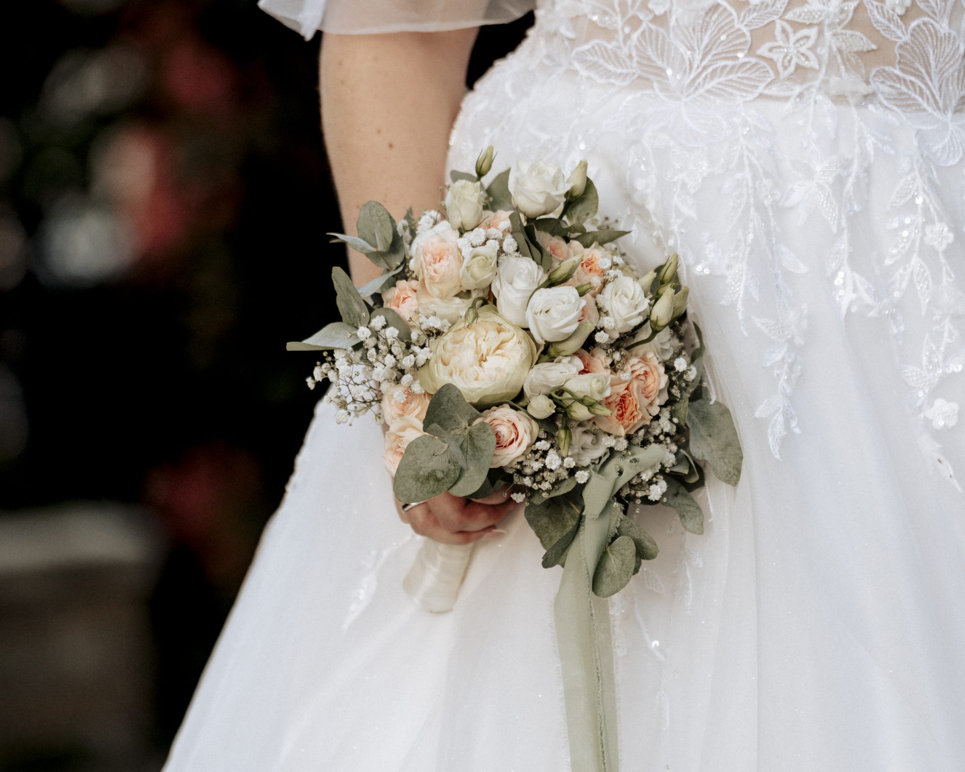 Brautstrauß in der Hand der Braut vor dem Spitzenkleid